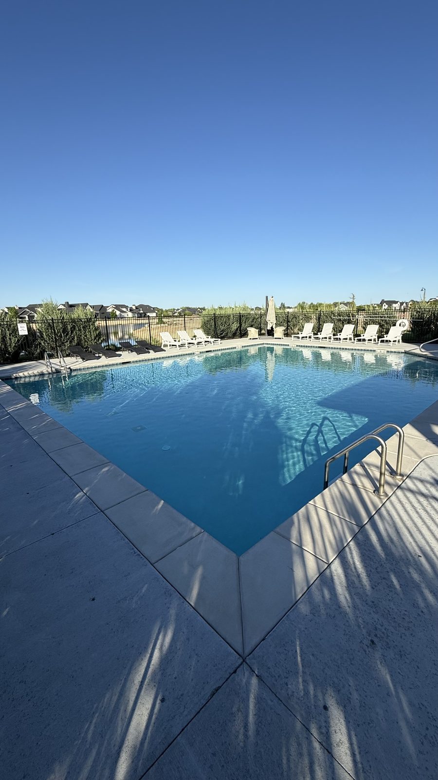 Community pool with lounge chairs on a clear day